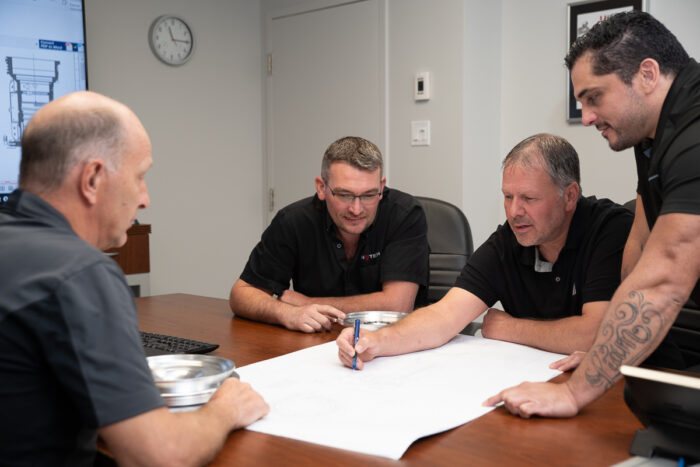Groupe d'employé discutant d'un projet d'envergure comme technicien au méthodes dans un local lumineux
