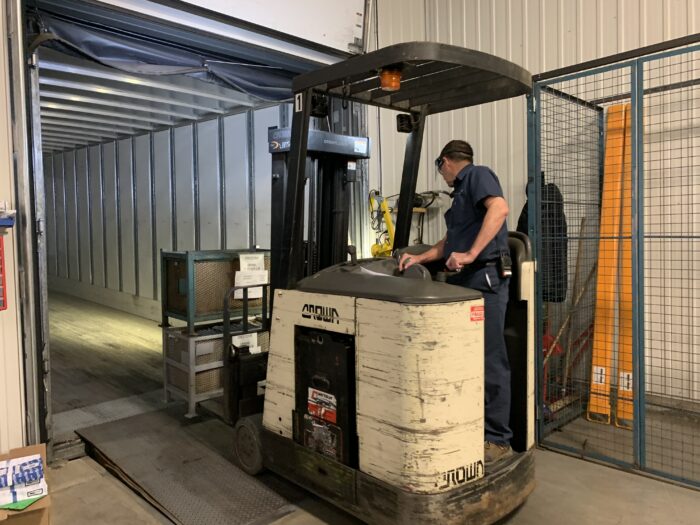 Commis à l'expédition heureux dans un environnement de travail dynamique utilisant un chariot élévateur pour expédition de commande à un client. 