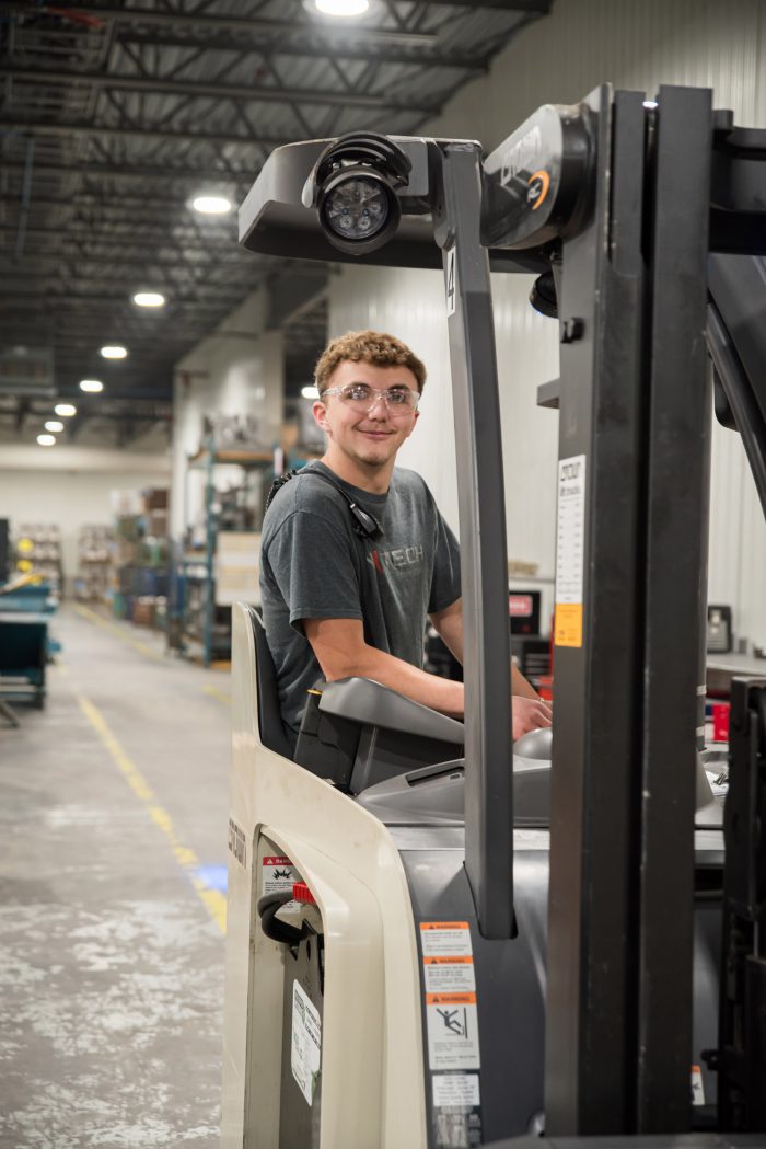 Employé heureux et souriant dans un environnement de travail sain et dynamique sur le chariot élévateur comme cariste (Quart de soi)r.